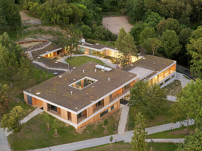 Celkový pohled z dronu zachycuje citlivé zasazení objektu do svahu s plynulým přechodem střechy do okolní krajiny.