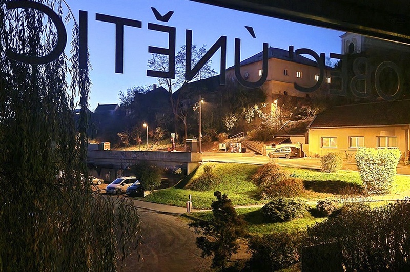 Pohled z&nbsp;okna obecního úřadu na&nbsp;náves, kterou v&nbsp;budoucnu čeká rekonstrukce (včetně rozšíření veřejného osvětlení). V&nbsp;pozadí původní budova únětického statku.